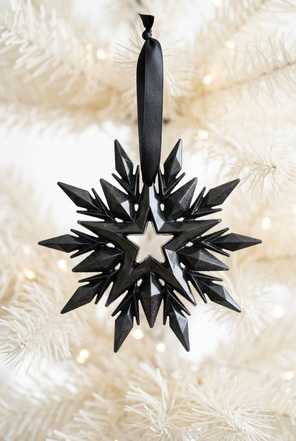 Black snowflake decoration against a softly blurred white Christmas tree